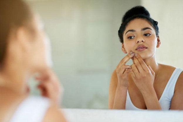 Woman observing face for hyperpigmentation 